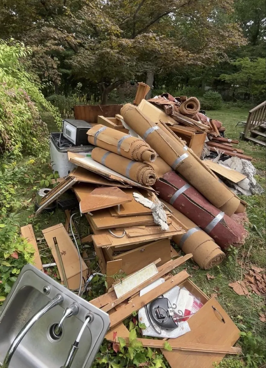 Backyard piled with carpet rolls, cabinets and a sink