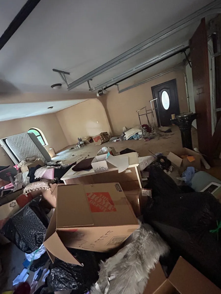 Cluttered garage with boxes and a mattress before cleanout