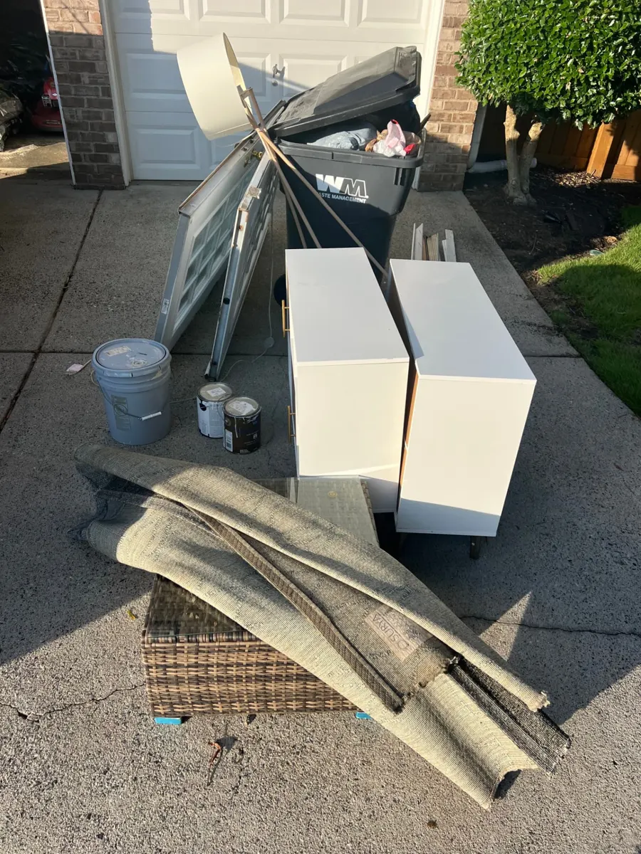 Dressers, rug, paint cans and wicker furniture in a driveway ready for pickup