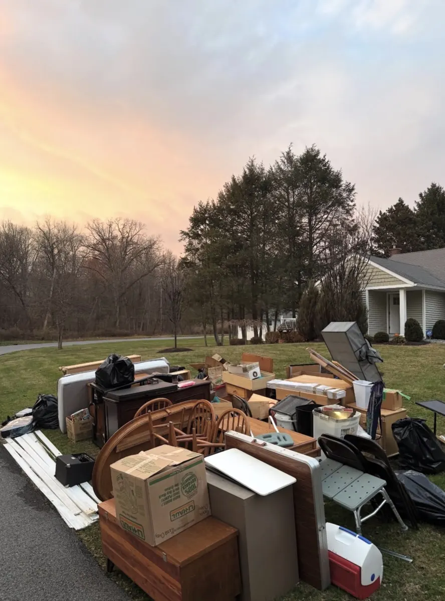 Large pile of furniture, boxes and chairs on a front lawn
