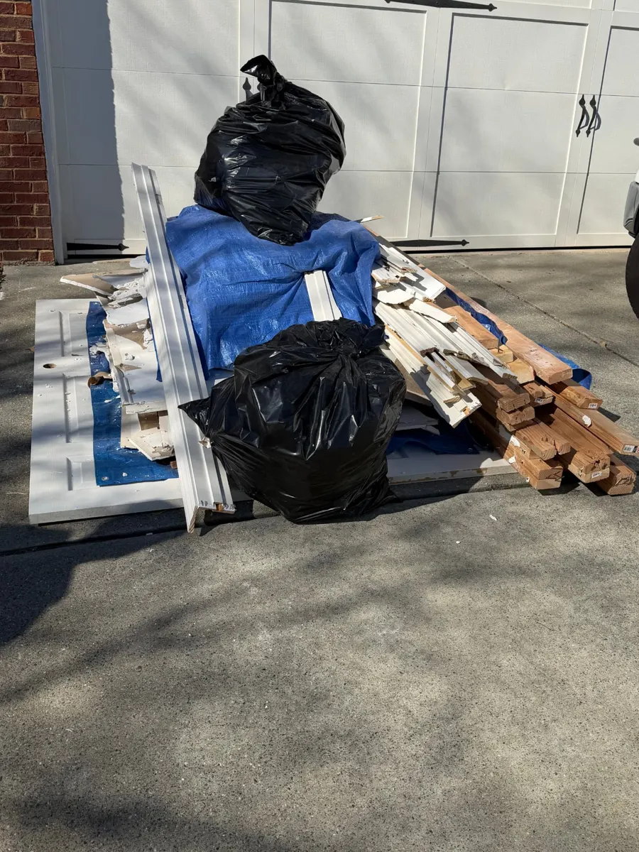 Renovation debris with lumber, trim and bags in a driveway