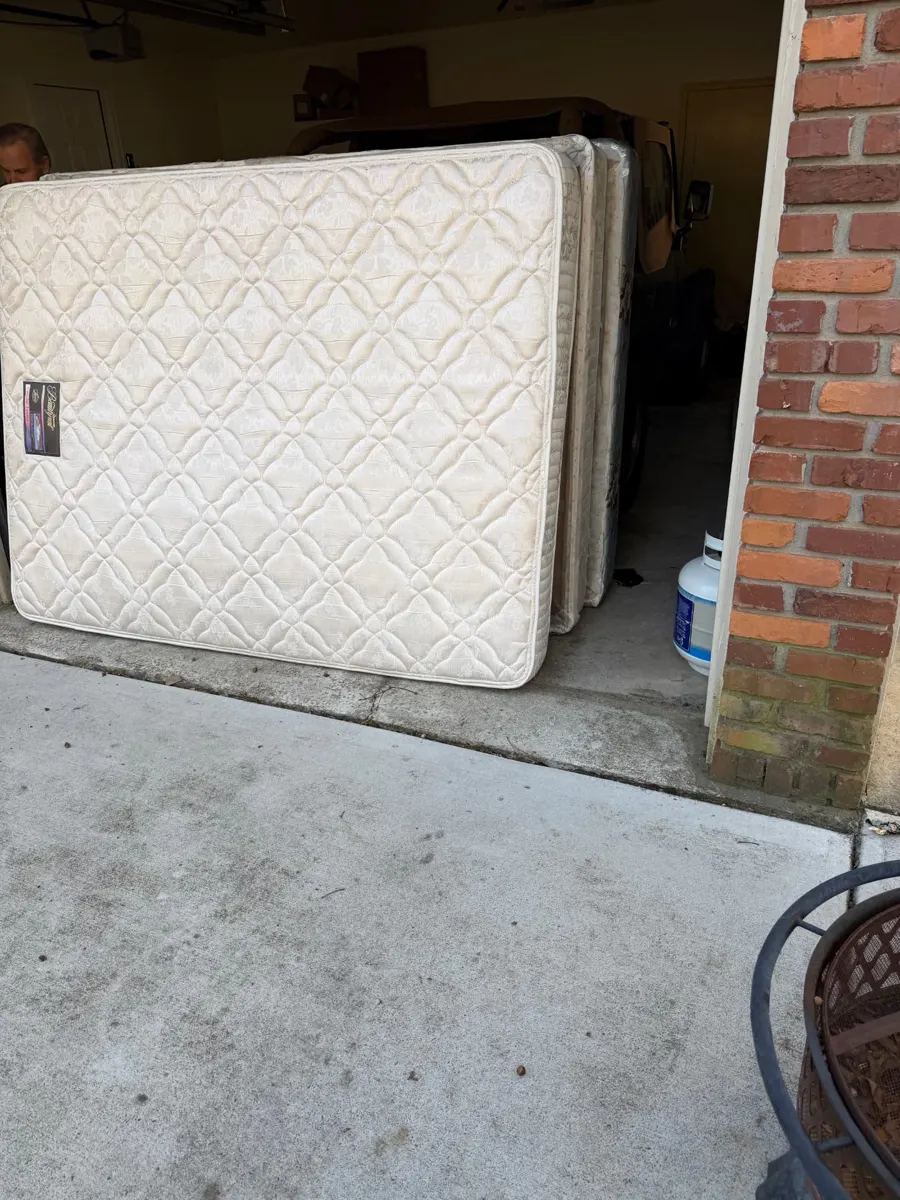 Several mattresses stacked in a garage ready for removal