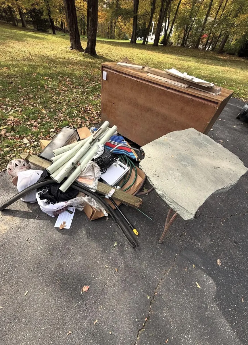 Dresser, stone table, pipes and hoses piled in a driveway