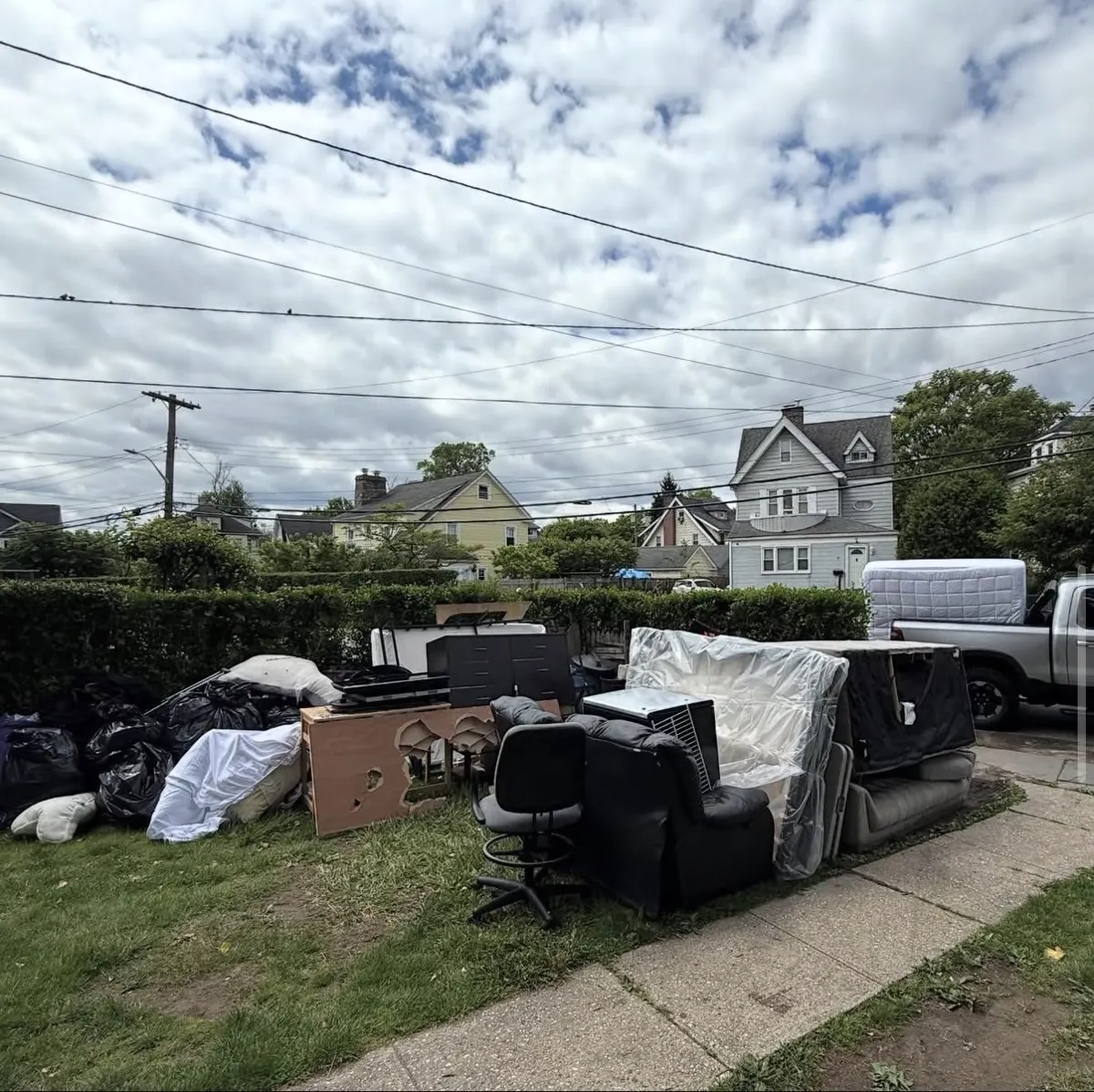 Sofas, dressers, recliner and bags piled at the curb