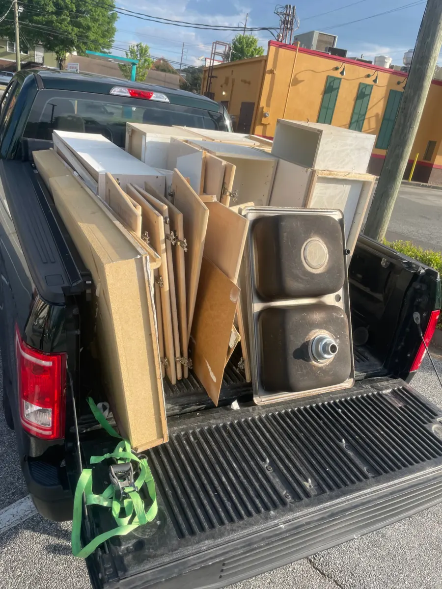 Pickup truck loaded with old kitchen cabinets and a steel sink