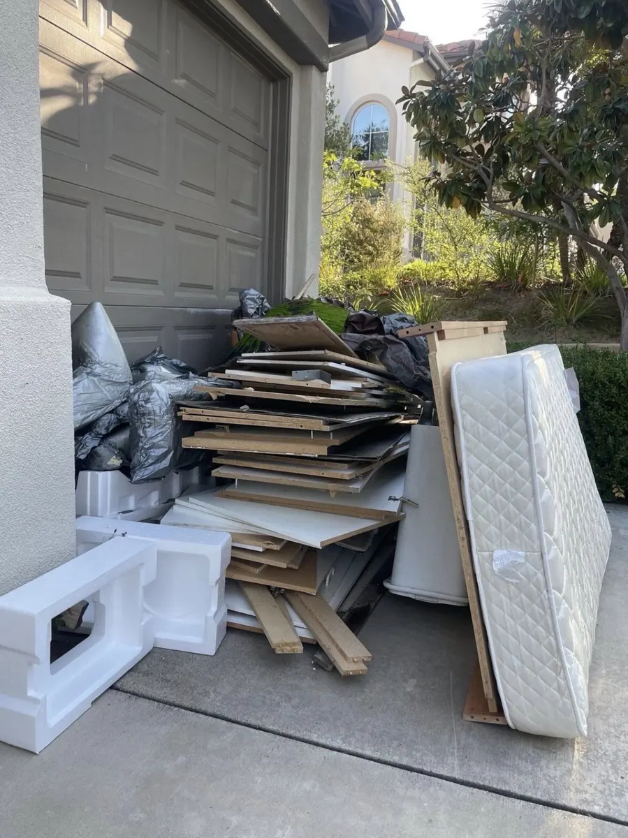 Mattress, particleboard and packing foam stacked by a garage