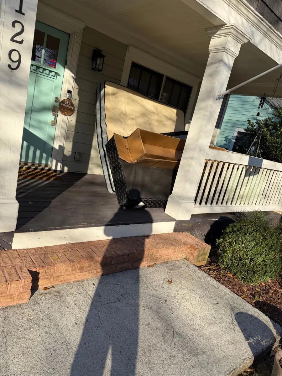 Mattress, box spring and boxes on a front porch before pickup